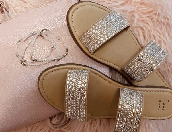 affordable must haves from target, image features embellished sandals a pink crossbody purse a pink fluffy heart pillow and a pink and gold bracelet set