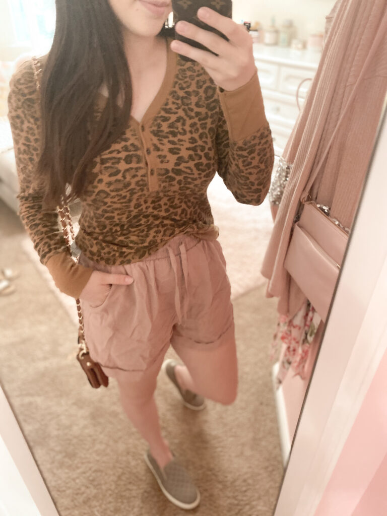 casual fall shorts outfit, dusty pink shorts with leopard waffle tee, taupe sneakers, louis vuitton phone case dupe, and black tweed headband