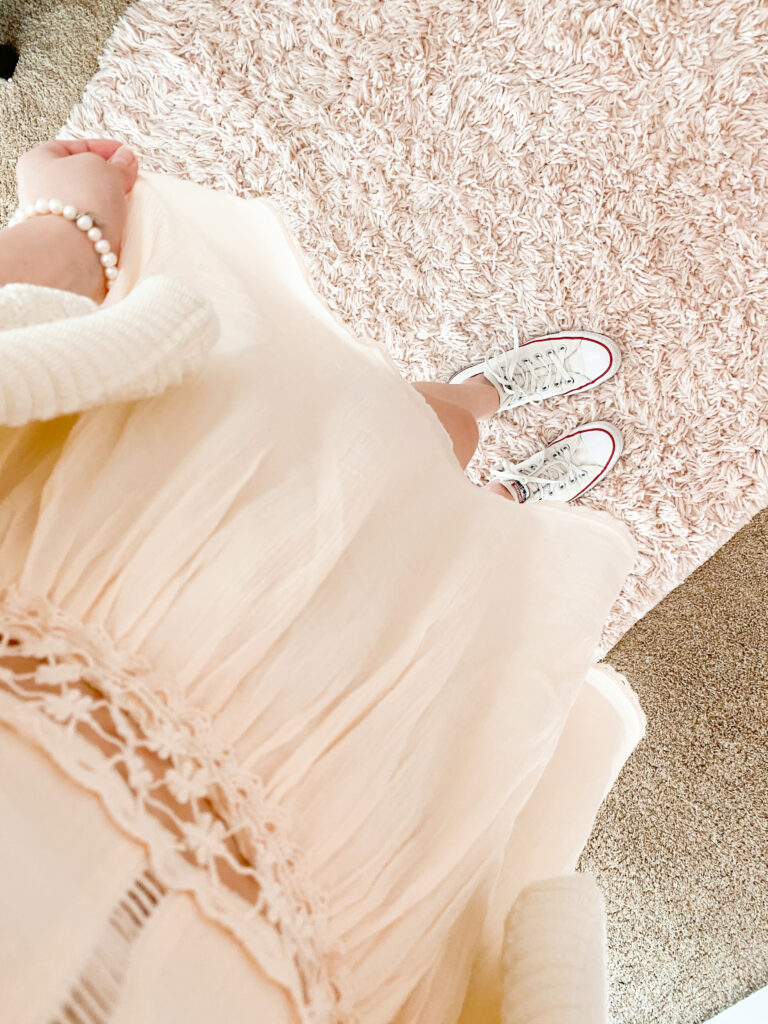 fashion blogger wearing all white monochromatic outfit with white crochet dress, white short sleeve cardigan, white low top converse, and white pearl bracelet